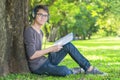 Young student in park listening to music on headphones Royalty Free Stock Photo