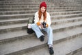Young student, photographer sits on street stairs and checks her shots on professional camera, taking photos outdoors Royalty Free Stock Photo