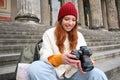 Young student, photographer sits on street stairs and checks her shots on professional camera, taking photos outdoors Royalty Free Stock Photo