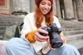 Young student, photographer sits on street stairs and checks her shots on professional camera, taking photos outdoors Royalty Free Stock Photo