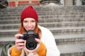 Young student, photographer sits on street stairs and checks her shots on professional camera, taking photos outdoors Royalty Free Stock Photo