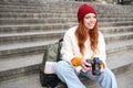 Young student, photographer sits on street stairs and checks her shots on professional camera, taking photos outdoors Royalty Free Stock Photo