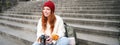 Young student, photographer sits on street stairs and checks her shots on professional camera, taking photos outdoors Royalty Free Stock Photo