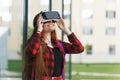 Young student plays with virtual reality glasses. Pretty girl looks at the world with 3D head mount