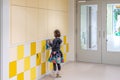 A young student puts her school supplies in a locker on a locker wall