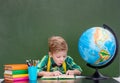 Young student reading a book near empty green chalkboard Royalty Free Stock Photo