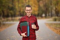 Young student in red checkered shirt with cap of coffee. Portrait of handsome young man holding folders Royalty Free Stock Photo