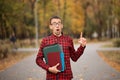 Young student in red checkered shirt point top. Portrait of handsome young man holding folders Royalty Free Stock Photo