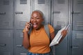 A young student screams with happiness on the phone in front of lockers