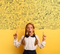 Young student is with shocked expression and indicates a complex exercise. Yellow background