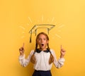 Young student is with shocked expression and indicates a graduation hat. Yellow background