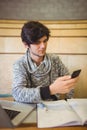 Young student sitting at desk and using mobile phone Royalty Free Stock Photo