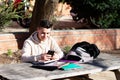 Young student sitting in a park while using a mobile phone on a wooden table Royalty Free Stock Photo