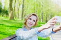 Young student smiling girl is taking selfie photo on smartphone camera outdoor, beautiful bokeh background, teenage trand Royalty Free Stock Photo