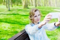 Young student smiling girl is taking selfie photo on smartphone camera outdoor Royalty Free Stock Photo