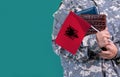 Young student soldier in uniform with books holds in hand Albania flag, close up Royalty Free Stock Photo