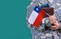 Young student soldier in uniform with books holds in hand Chile flag, close up Royalty Free Stock Photo