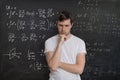 Young student is solving math exam. Mathematics formular on blackboard in background Royalty Free Stock Photo