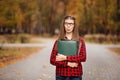 Young student with surprised face looks out of folder in red checkered shirt. Portrait of clever young woman