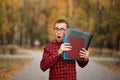 Young student with surprised face looks out of folder in red checkered shirt. Portrait of handsome young man Royalty Free Stock Photo