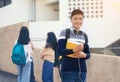 Young student teenager boy or high school student carrying schoolbag holding notebooks with friends in background Royalty Free Stock Photo