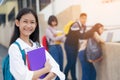 Young student teenager girl high school student carrying schoolbag holding notebooks with friends in background Royalty Free Stock Photo