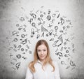 Young student is thinking about education at business school. Drawn business icons over the concrete wall. Royalty Free Stock Photo