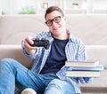 Young student trying to balance studying and playing games Royalty Free Stock Photo