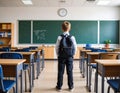Schoolboy with backpack standing alone in empty classroom Royalty Free Stock Photo