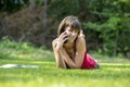 Young student using her mobile phone in the park lying on the gr Royalty Free Stock Photo