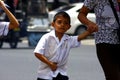 A young student walks with his mother going to school.