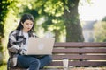 Young student watching lesson online and studying from park. Woman college university student using laptop computer