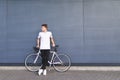 Young student with a white bike stands against the wall and looks to the side. Sports concept Royalty Free Stock Photo
