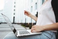 Young student woman sits in city park with modern laptop. Close-up hands and laptop Royalty Free Stock Photo