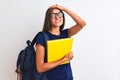 Young student woman wearing backpack glasses holding book over isolated white background stressed with hand on head, shocked with Royalty Free Stock Photo