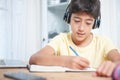 Young student writing with a pen on a notepad on a desk. Royalty Free Stock Photo