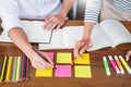 Young students classmates help friend catching up workbook and learning tutoring in a library, education and school concept Royalty Free Stock Photo