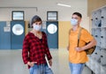 Young students friends with face masks back at college or university, coronavirus concept.