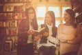 Young students girls in library reading book together and Royalty Free Stock Photo