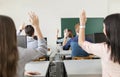 Young students raising hands in a classroom Royalty Free Stock Photo