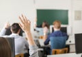 Young students raising hands in a classroom