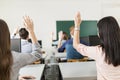 Young students raising hands in a classroom