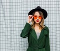 Young style woman in sunglasses and green cloak in 90s style