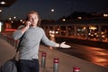 Young stylih man alking through the night treet near the road and having a conversation on the phone Royalty Free Stock Photo