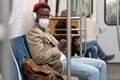 Young African American man in glasses sitting in subway train wear face mask listening to the music. Royalty Free Stock Photo