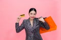 Young Stylish Asian woman carrying shopping bags and holding credit card. Beautiful fashionable woman isolated over pink Royalty Free Stock Photo