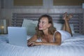 Young stylish attractive and beautiful Caucasian woman 30s lying on bed at night in home bedroom using internet at laptop computer Royalty Free Stock Photo