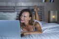 Young stylish attractive and beautiful Caucasian woman 30s lying on bed at night in home bedroom using internet at laptop computer Royalty Free Stock Photo