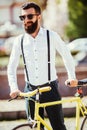Young stylish bearded man with a fixie bicycle on the sunny street