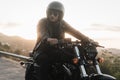 Young stylish biker sitting on his vintage motorcycle, wearing leather jacket and helmet Royalty Free Stock Photo